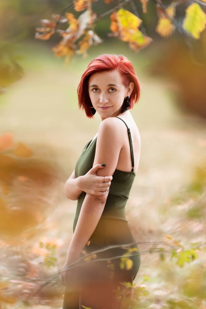 senior portrait creatively framed through fall leaves